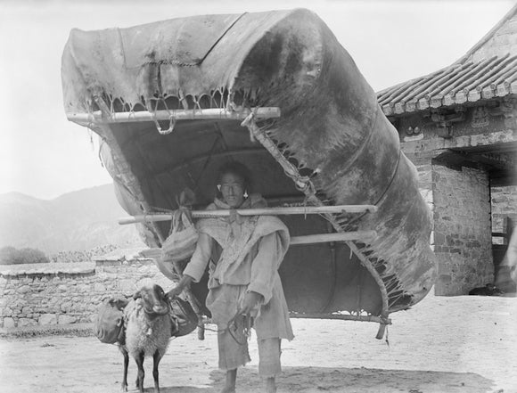 Man carrying hide boat by Yuthok bridge